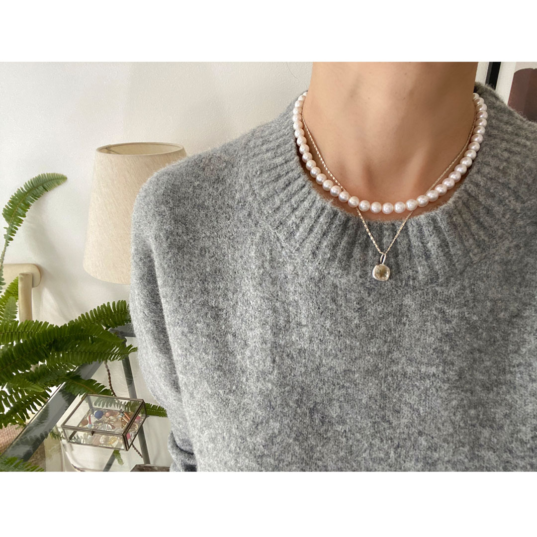 シルバーチェーンネックレスとパールネックレスを身につけた女性