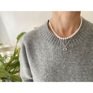 水晶のペンダントとパールネックレスを身につけた女性