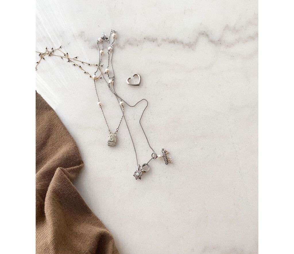 シルバーのハートイヤーカフとネックレスを大理石の上に並べたスタイリング写真